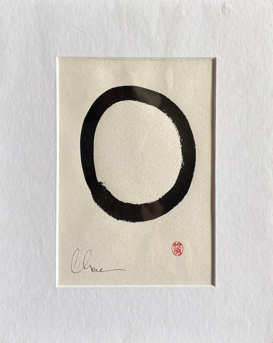 Black circular brushstroke on beige paper with a signature and seal, framed in white.